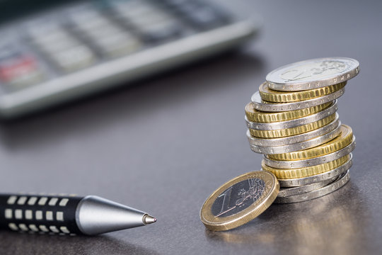 Eurom&uuml;nzen, Stift und Taschenrechner auf spiegelnder Tischplatte