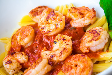 Pasta with fresh sauce and shrimps on a white plate background.