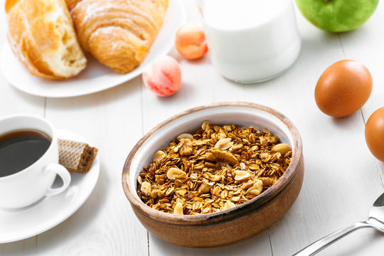 Granola, croissant, milk and fruits on a table. Healthy breakfast with coffee. International vegetarian meal. Top view.