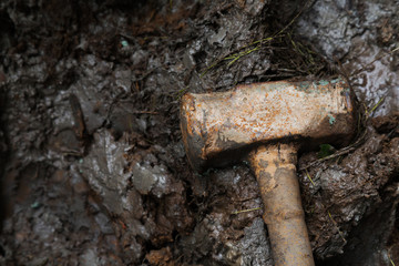 old rusty iron construction hammer on the mud