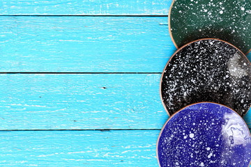 Three ceramic handmade plates of blue, green and black with space cosmic abstract pattern of white spots on blue boards background