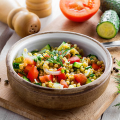 Traditional Israeli healthy meal Ptitim with tomatoes, cucumber and onion for delicious healthy breakfast. Cooking of classic Moroccan couscous with vegetables.
