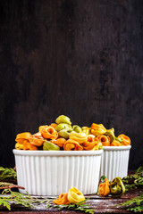 Raw italian pastani tortellini with flour in white plate on black wooden background, place for text