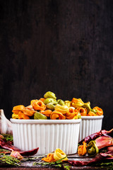 Raw italian pasta tortellini with flour in white plate on black wooden background, place for text