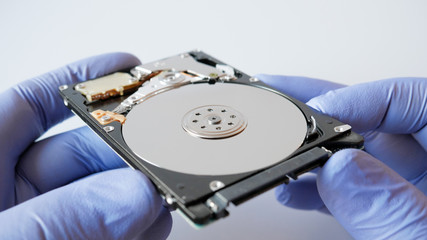 Disassembled hard disk drive in male hand on white background