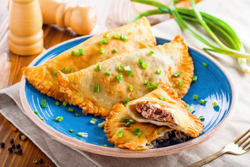 Chebureki with meat and spring onion. National Russian, Turkish, Ukrainian, Tatar and Romanian food on a table. Middle East traditional meat pastry.