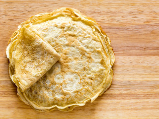 Stack of pancakes on a wooden board, top pancake is folded