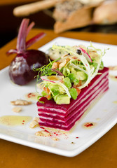 A beautiful gourmet, organic sliced beetroot salad, served with avocado, tomato, onion, nuts, reddish, onion and olive oil.