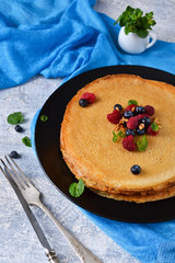 Homemade pancakes with raspberries and blueberries on a concrete background