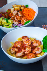 Fresh pasta with shrimp and tomato sauce with basil in a white bowl.