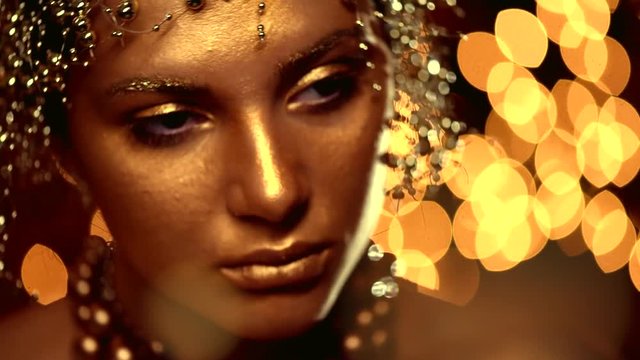 Fashion art golden skin woman face portrait closeup. Glamour shiny professional makeup. 4K Slow motion UHD video