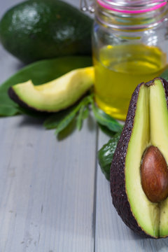 Green ripe avocado with leaves and organic avocado oil