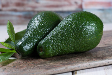 Green ripe avocado with leaves on granite plank
