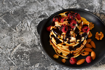 Homemade Pancake with raspberries, nuts and chocolate on a stone background