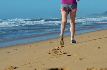 Fitness and running on beach, woman runner legs in shoes on sand near sea, healthy lifestyle and sport concept
