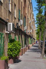 Calle arbolada con edificio con aparatos de aire acondicionado