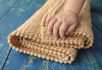 warm soft blanket and a child's hand, a wooden surface