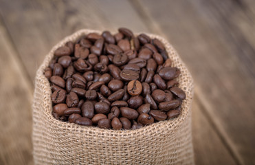 Coffee beans in burlap on wooden background. Top view. 