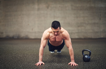 Obraz premium Young sportive male doing push-ups in gym