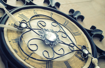 Old vintage wall clock with roman numbers and ornamental metal author design heart instead of clockwise. Abstract composition for your design