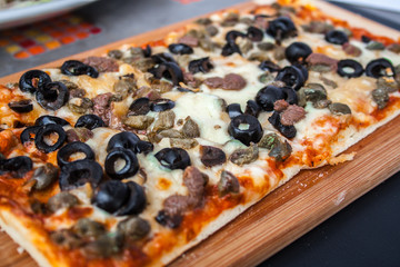 Pizza con hongos, queso y tomate en una tabla de madera.