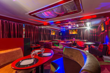 Stylish karaoke bar with armchairs and displays on walls