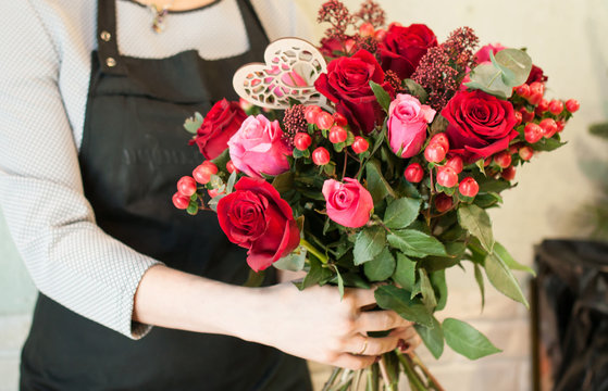 Girl collects a florist bouquet of roses. Wedding preparations. Workplace