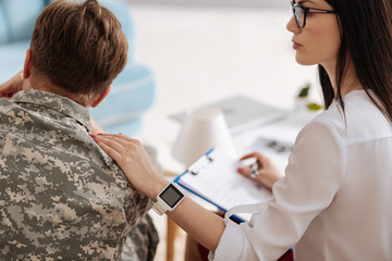 Obraz premium Pleasant nice therapist putting her hand on the soldiers shoulder