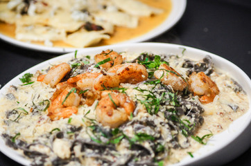 Fresh pasta with shrimp and tomato sauce with basil in a white bowl.