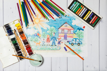 Hand drawn Bright Colorful Childrens Sketch With Happy Family, House, Dog, Car on the Lawn with Flowers with lying flat pencils, paints and pastel - concept of children creativity, close up top view