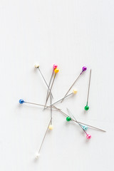 color pins for sewing on a white background, top view.