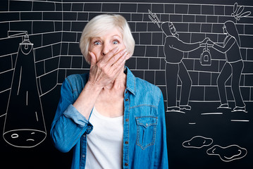 Shocked aged woman covering her mouth