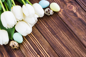 Bouquet white  tulip flowers with easter eggs on old wooden table. Place for text.