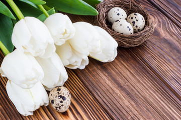 Bouquet white  tulip flowers with easter eggs on old wooden table. Place for text.