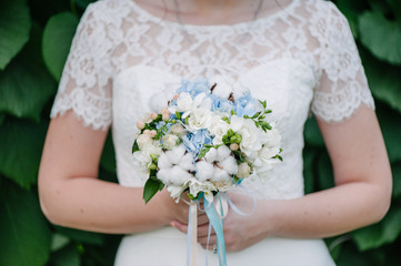 Bride holding delicate marriage bouquet with bow