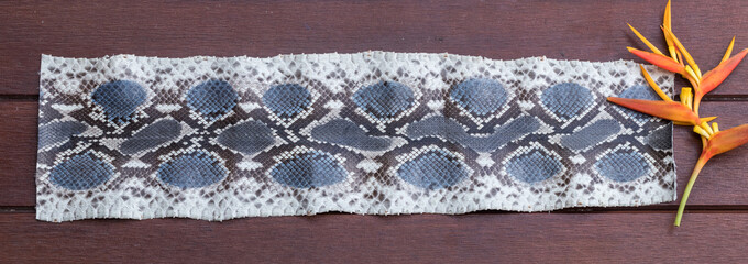 Python snakeskin leather, python skin. Small piece on a wooden background.