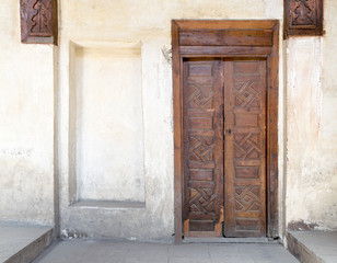 Wooden aged closed decorated door and beige plaster wall, Medieval Cairo, Egypt