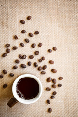 Cup of black coffee with beans on Burlap Surface