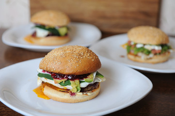 Burgers on white plates on a wooden background