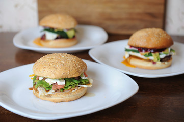 Burgers on white plates on a wooden background