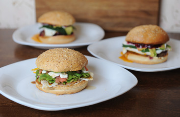 Burgers on white plates on a wooden background