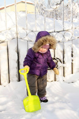 Cute little girl playing with a small yellow spatula in winter
