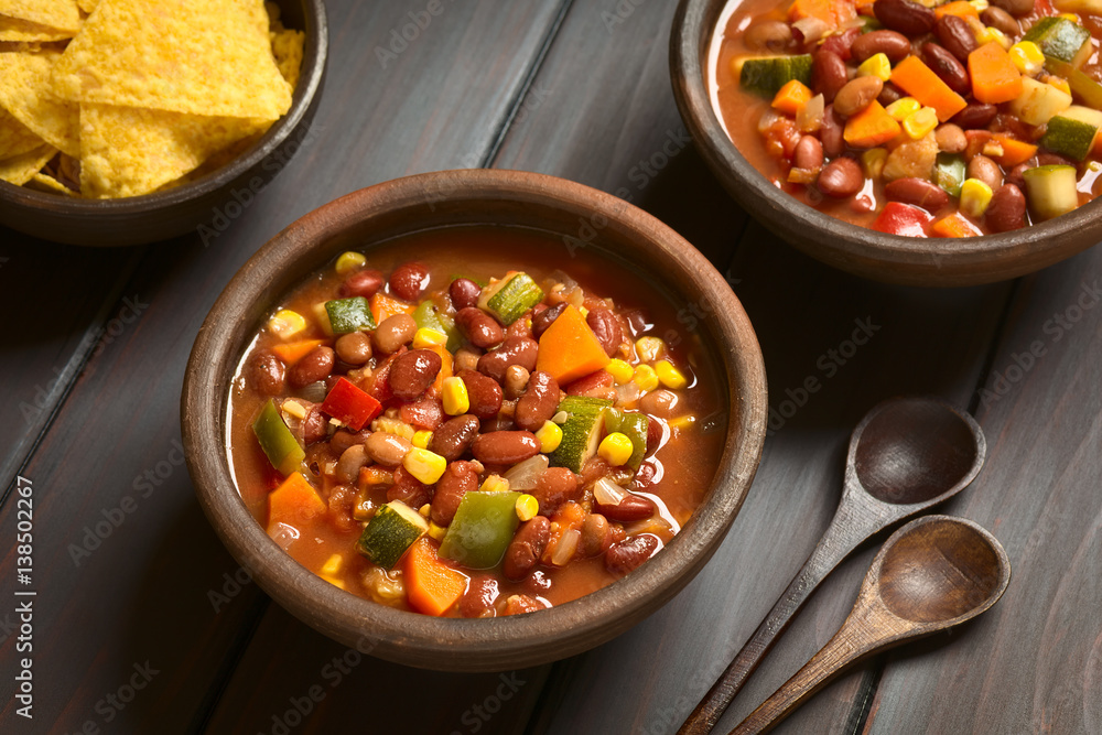 Poster Vegetarian chili dish made with kidney bean, carrot, zucchini, bell pepper, sweet corn, tomato, onion, garlic, photographed with natural light (Selective Focus, Focus in the middle of the first dish)