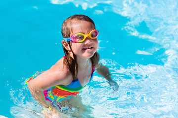 Child learning to swim in pool