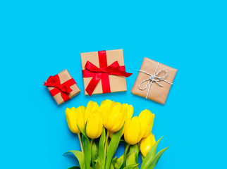 bunch of yellow tulips and beautiful gifts on the wonderful blue background