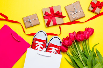 bunch of red tulips, red gumshoes, cool shopping bags, ribbon and beautiful gifts on the wonderful...