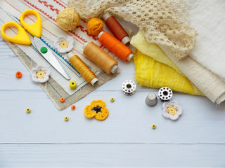 Fototapeta na wymiar Composition of yellow accessories for needlework on wooden background. Knitting, embroidery, sewing. Small business. Income from hobby.
