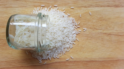 Pouring thai jasmine rice from glass bowl to plain wood