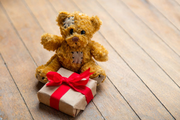 cute teddy bear holding beautiful small gift on the wonderful wooden brown background