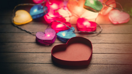 Obraz na płótnie Canvas beautiful colorful heart shaped garland and opened heart shaped box on the wonderful brown wooden background